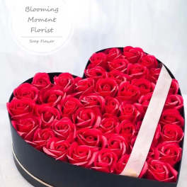 Heart-shaped box filled with red roses and a ribbon