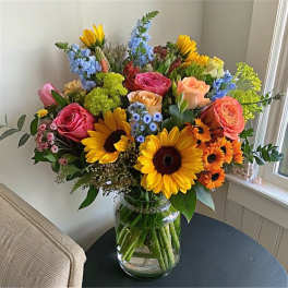 Colorful mixed bouquet with sunflowers and roses in a glass vase