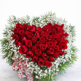 Heart-shaped bouquet of red roses with white baby's breath and a heart ribbon