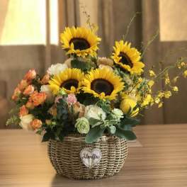 Sunflower and rose arrangement in a woven basket