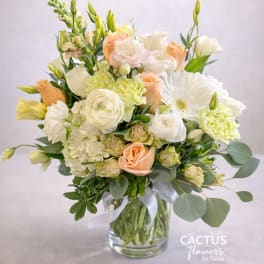Pastel bouquet of roses, ranunculus, and white blooms in a glass vase