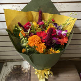 Colorful mixed bouquet wrapped in green and yellow paper with a ribbon