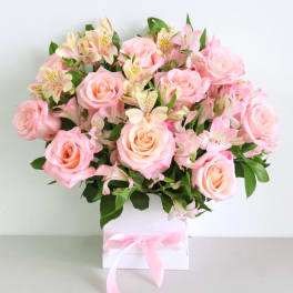 Pink roses and pale alstroemeria in a white box tied with a pink ribbon
