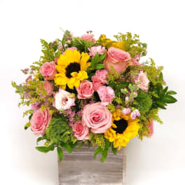 Pink roses and sunflowers in a wooden box