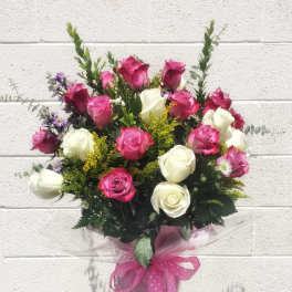 Bouquet of pink and white roses with small purple flowers in a wrapped vase