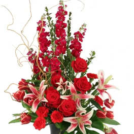 Red roses and lilies arranged in a black vase