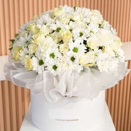 White roses and daisies arranged in a white hatbox