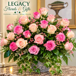 Pink and peach roses in a decorative vase with trailing ivy