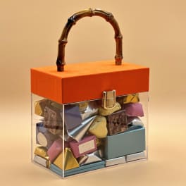Clear gift box with assorted chocolates and an orange lid with handle