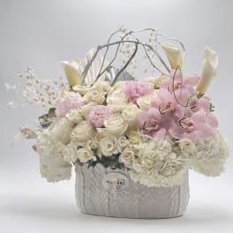 White roses and pink orchids arranged in a textured silver vase