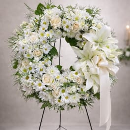 White floral wreath on a stand with a ribbon bow