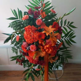 Tall orange and red floral standing spray with ribbon