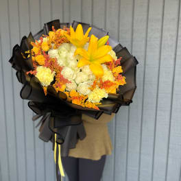 Yellow lilies and white roses in a black-wrapped bouquet