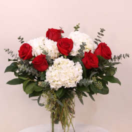 Red roses and white hydrangeas in a clear glass vase