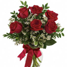 Red roses in a clear glass vase with a red ribbon