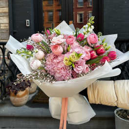 Large pink bouquet wrapped in white paper with a peach ribbon