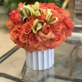 Orange rose bouquet with green orchids in a white vase