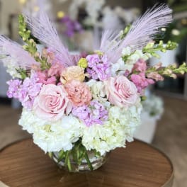 Pink roses and pastel flowers arranged in a clear glass vase