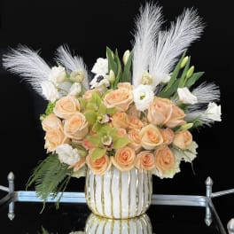 Peach roses and white flowers in a white-and-gold vase