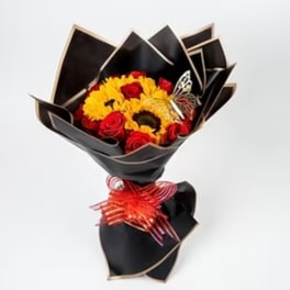 Bouquet of red roses and yellow sunflowers wrapped in black paper with a red ribbon