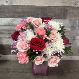 Bouquet of red, pink, and white flowers in a purple glass vase