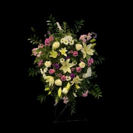 Standing floral spray with lilies, roses, and mixed blooms on an easel