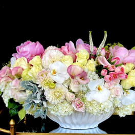 Large pastel floral arrangement in a white pedestal vase