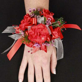 Red floral wrist corsage with ribbon on a hand