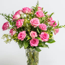Pink roses in a clear glass vase with green filler