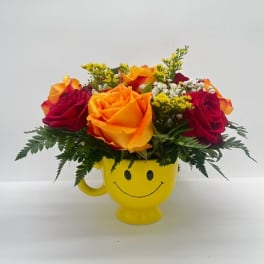 Bouquet of red and orange roses in a yellow smiley-face mug