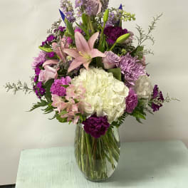 Mixed bouquet of pink, purple, and white flowers in a glass vase