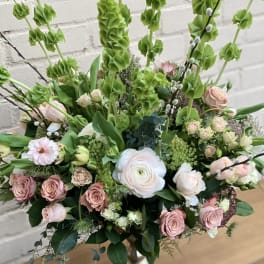 Tall bouquet of pink and white roses with green blooms in a silver vase