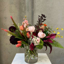 Mixed bouquet in a clear glass vase with pink, burgundy, and orange blooms