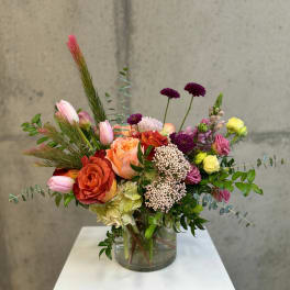 Mixed bouquet in a clear glass vase with roses, tulips, and purple blooms