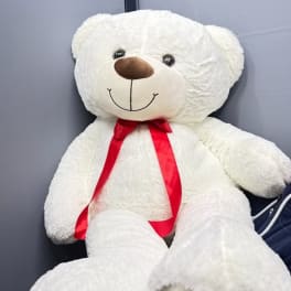 Large white teddy bear with a red ribbon bow