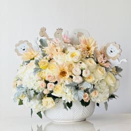Pastel floral arrangement in a white bowl with animal picks