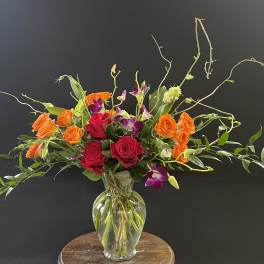 Mixed roses and orchids in a clear glass vase