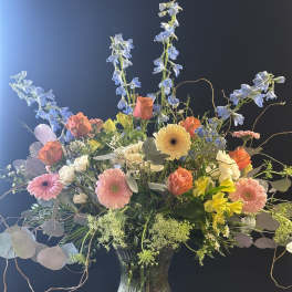 Mixed bouquet in a glass vase with blue delphinium and pink gerbera daisies