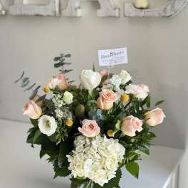 Bouquet of peach and white roses with hydrangea in a glass vase