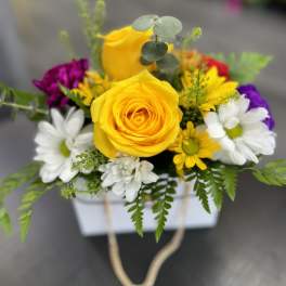 Yellow roses and white daisies in a white box with rope handles