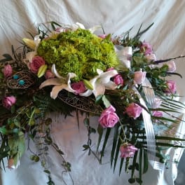Large floral spray with pink roses, white lilies, and green blooms