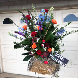 Tall mixed flower arrangement in a basket with a fishing sign