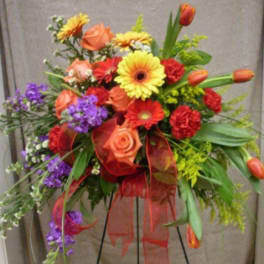Colorful standing floral arrangement with roses, gerbera daisies, tulips, and ribbon