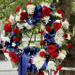 Large wreath of red and white flowers with blue ribbons on an easel