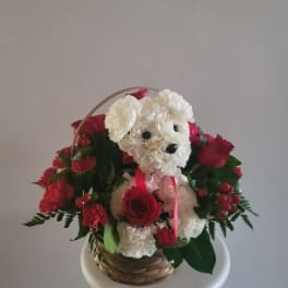 Basket arrangement with a white plush dog and red roses