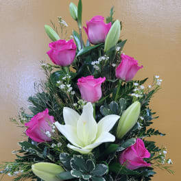 Pink roses and white lilies arranged in a red glass vase