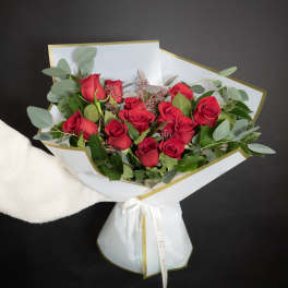 Bouquet of red roses wrapped in white paper with gold trim