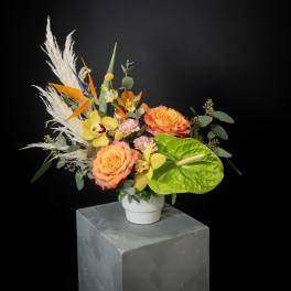 Tropical bouquet with orange roses and yellow orchids in a white vase