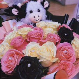Bouquet of pink, cream, and black roses with a plush cow toy