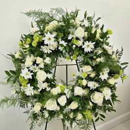 Large white and green floral wreath on a stand
